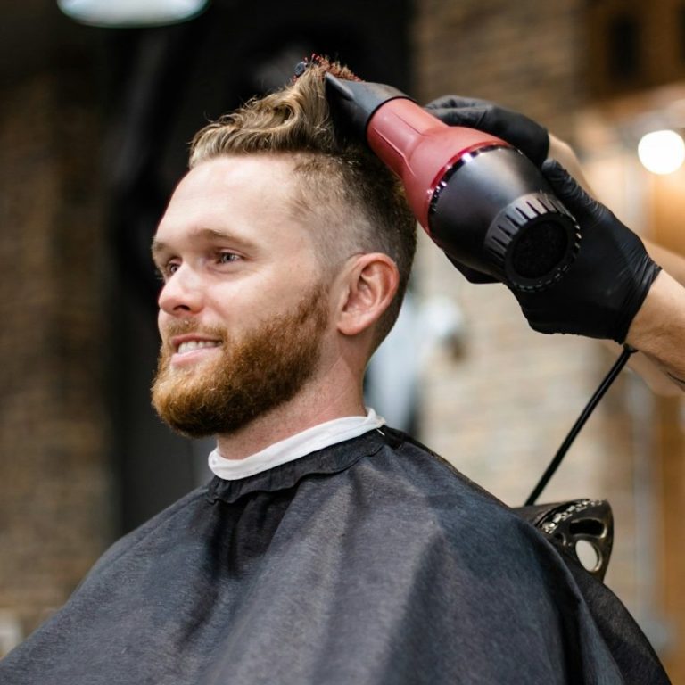 Nahaufnahme einer Hand, die einen Haarschnitt mit einer elektrischen Maschine durchführt.